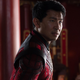 Simu Liu wearing a red superhero suit in a red room in a scene from Marvel's Shang-Chi and the Legend of the Ten Rings.